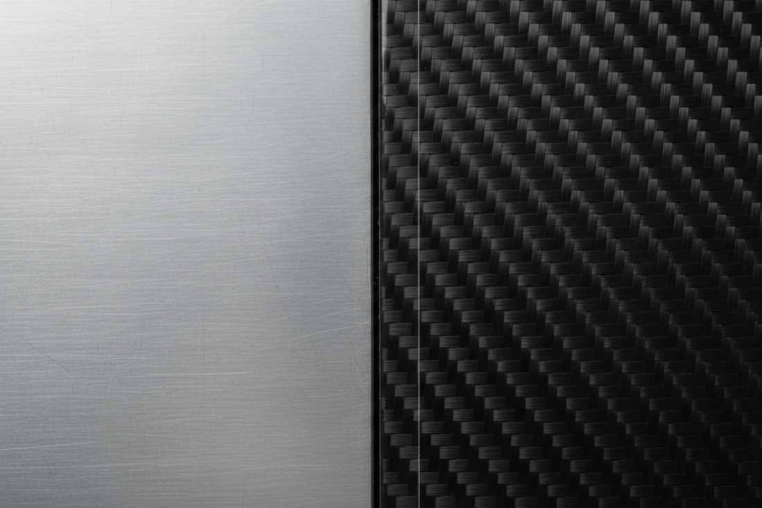 Adjacent flawless aluminum and carbon-fiber aircraft panels meeting at a clean seam under soft light