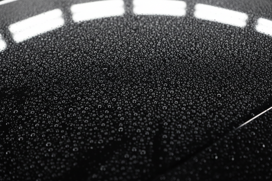 Glossy car hood covered in tight fresh water beads showing an even hydrophobic finish