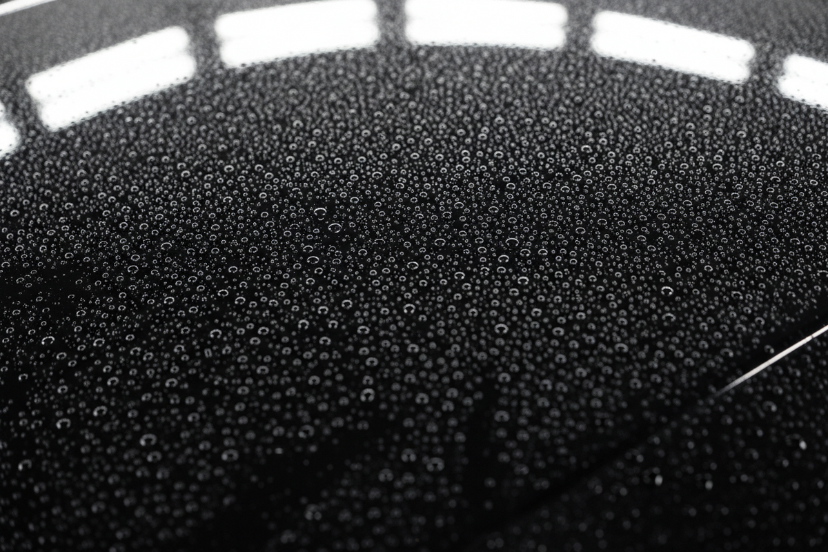 Glossy car hood covered in tight fresh water beads showing an even hydrophobic finish
